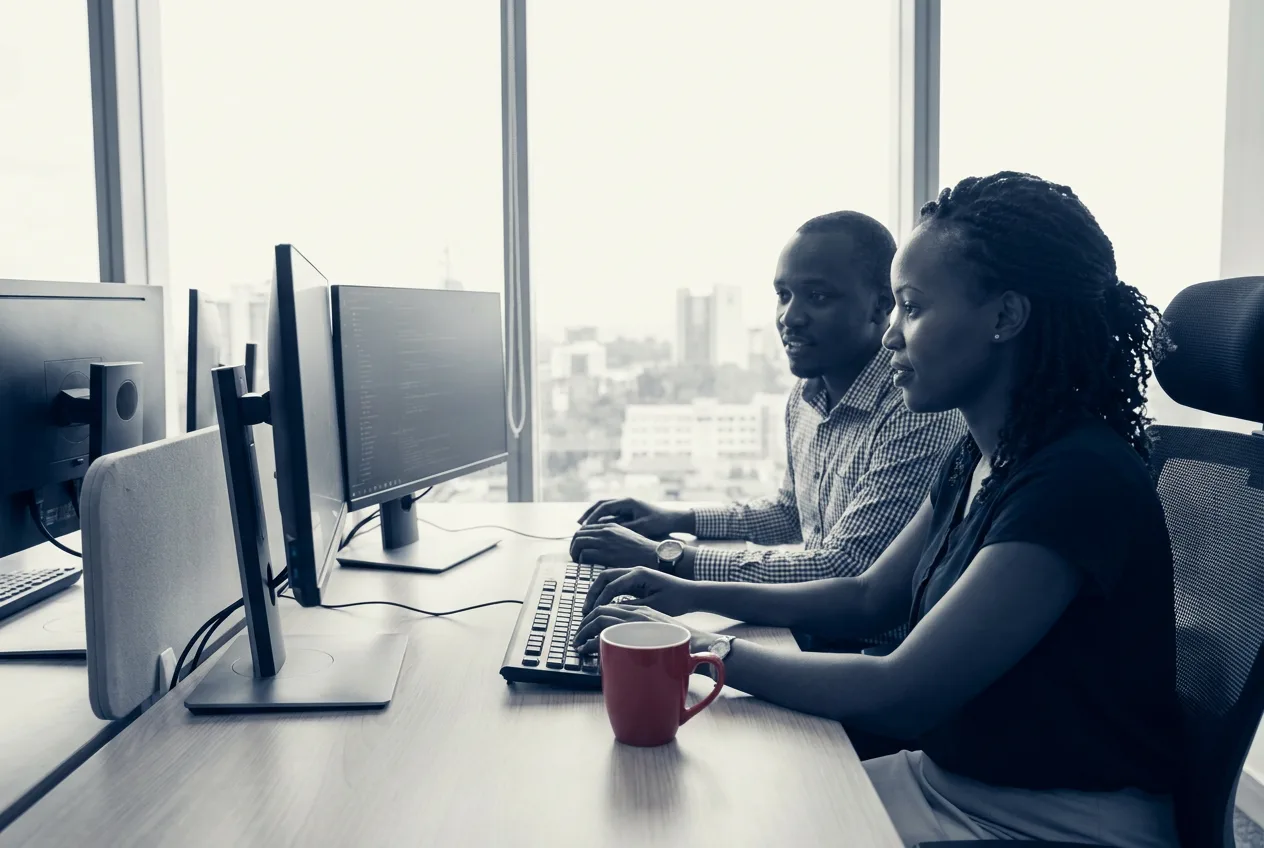 Software developers pair-programming at a workstation in a Nairobi office